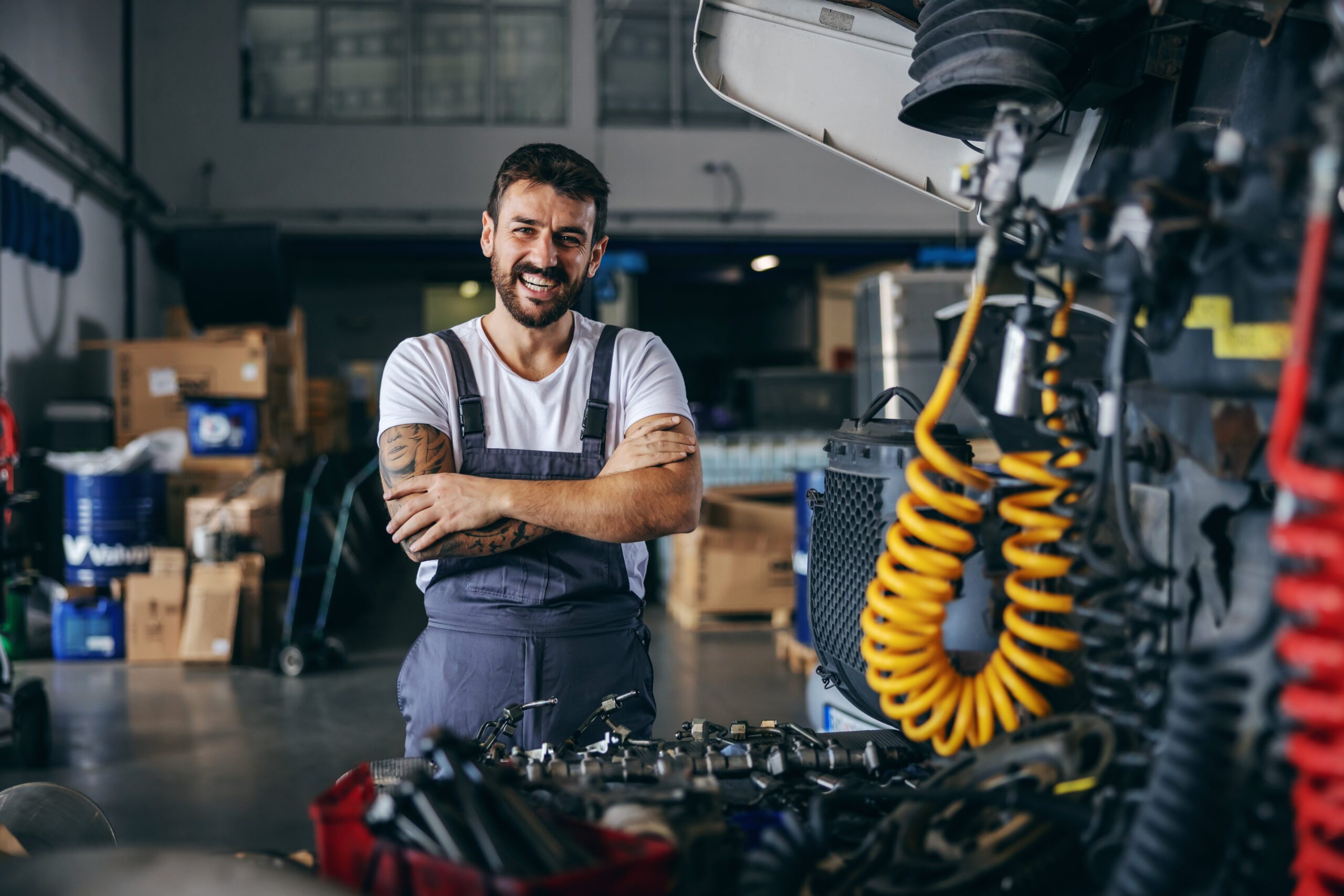 Smiling happy bearded tattooed worker from SSI Refugee Employment Support Program in his job as a mechanic