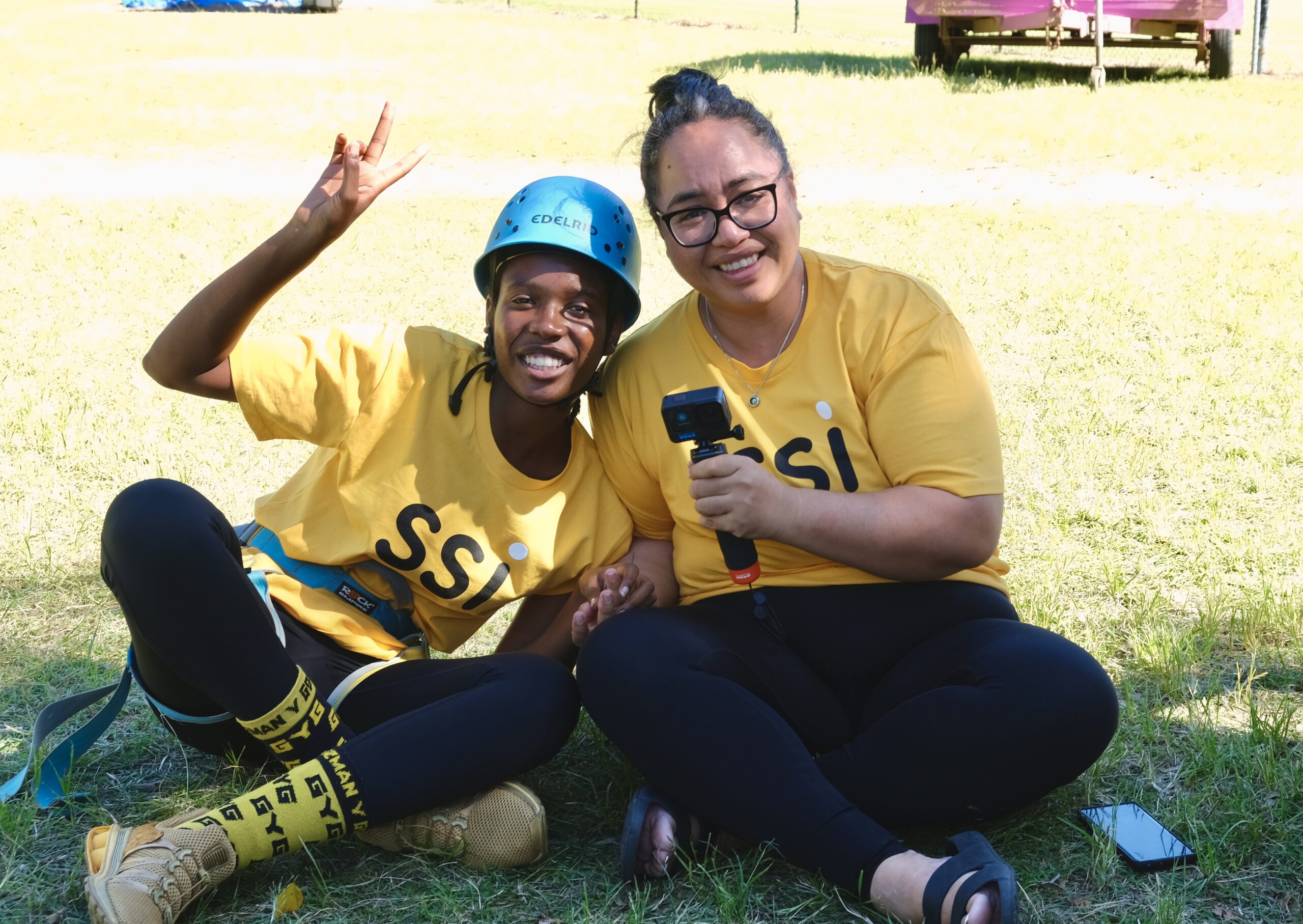 Young people from Youth Transitions Support program smiling while sitting on the grass