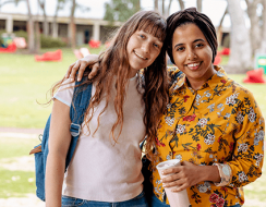 Two women stand smiling