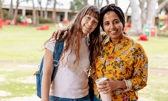 Two women stand smiling