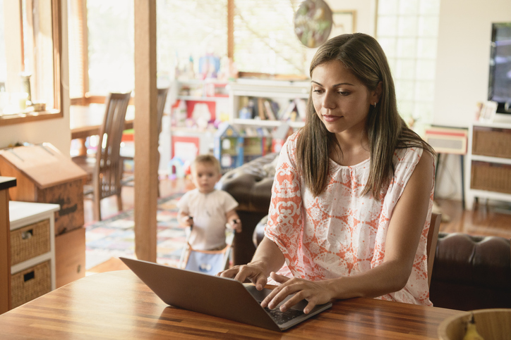 Mother from SSI Return To Work employment program types on her laptop with her child in the background