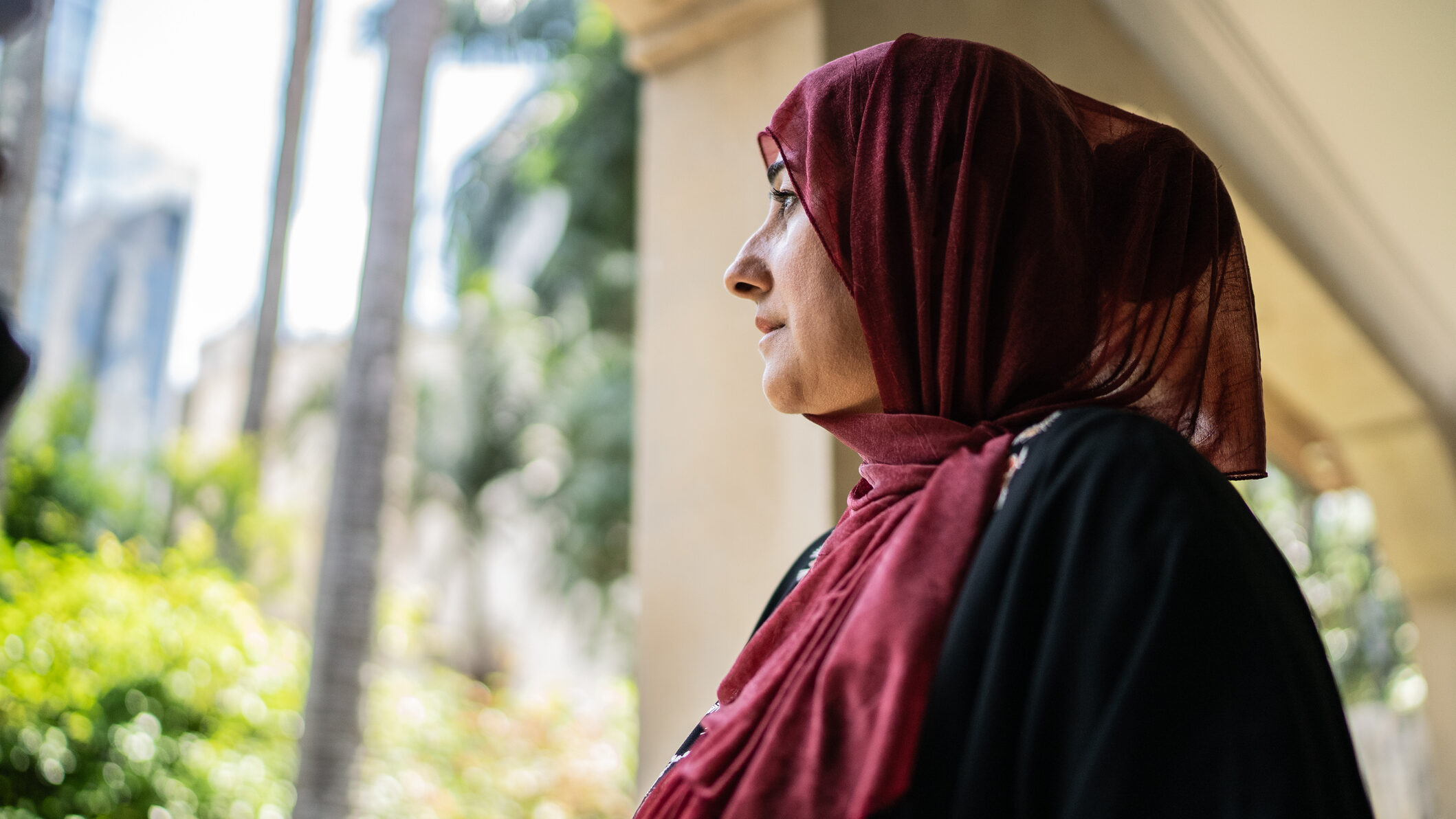 A woman in hijab looking outside from balcony