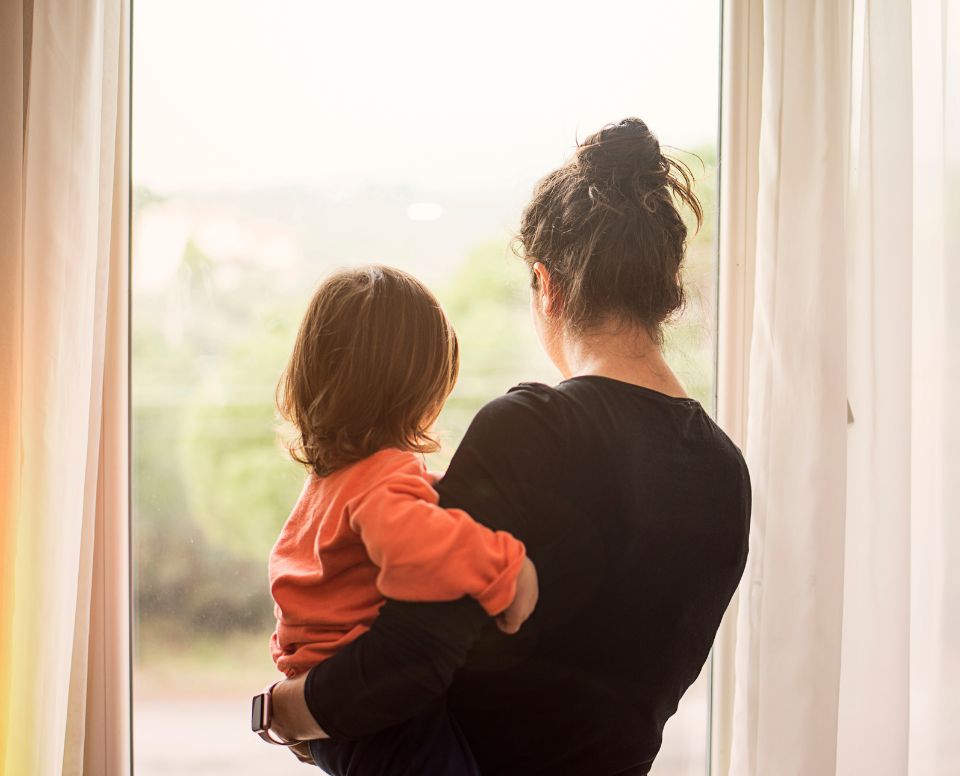 Woman and child looking out of house window