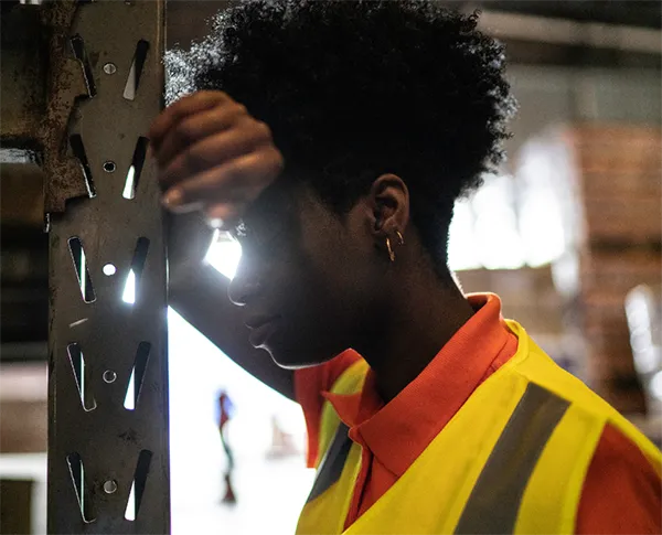 Worker resting on shelving in a warehouse