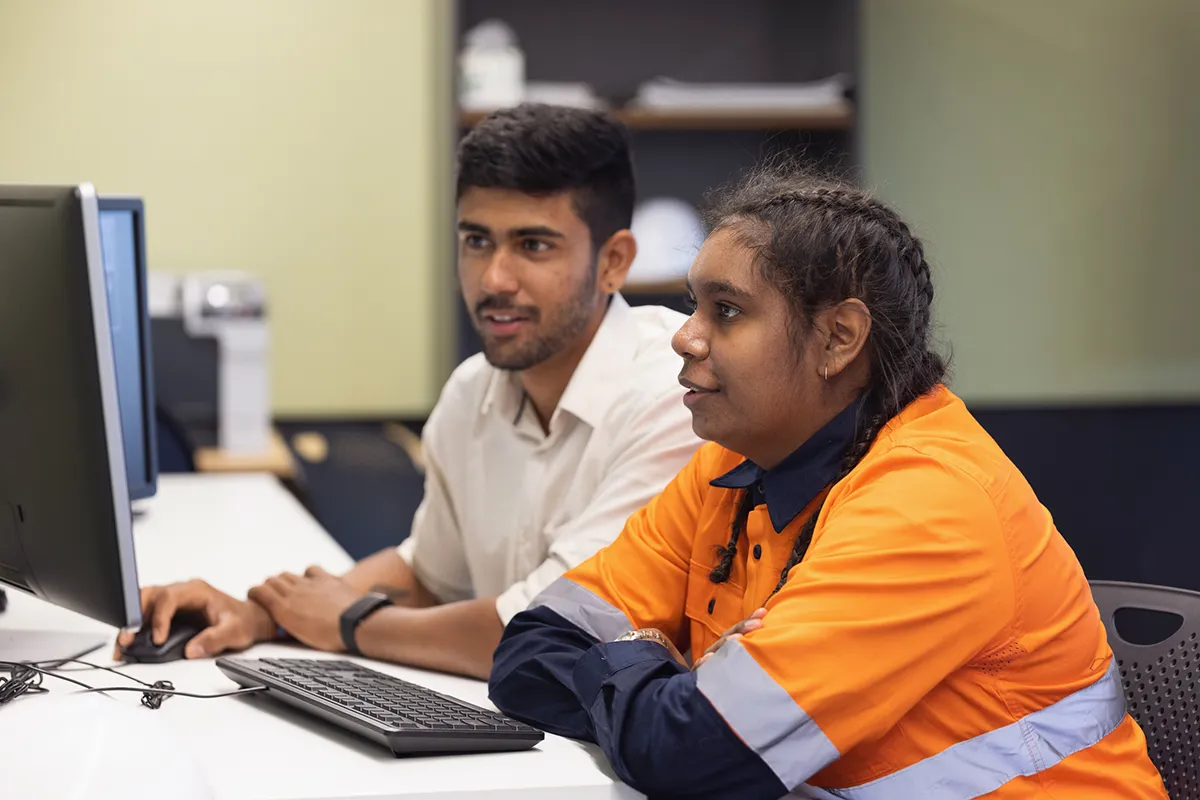 Two people sitting at a computer screen evaluating SSI programs