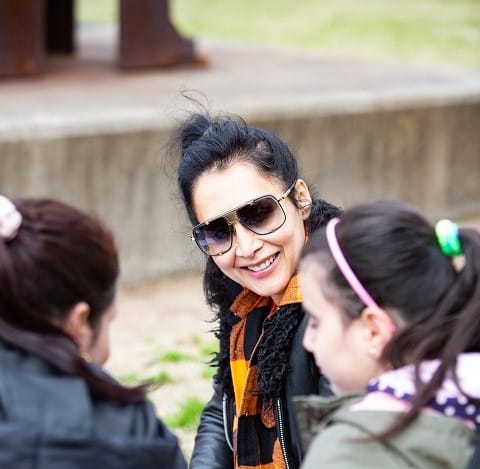 Female volunteer chatting with two young girls on an excursion in Sydney.