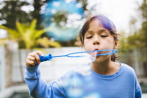 Child blowing bubbles with bubble wand