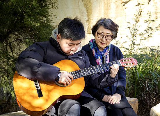 Child playing guitar with grandmother 